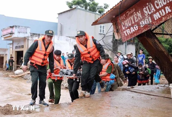 Các lực lượng chức năng đưa thi thể nạn nhân bị lũ cuốn trôi về để giao cho gia đình lo hậu sự. (Ảnh: Quý Trung/TTXVN)