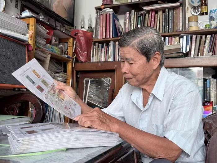 Ông Trần Hữu Huệ xem bì thư dán tem về Hoàng Sa được gửi từ nước ngoài, một hiện vật quý trong bộ sưu tập tem về chủ quyền biển, đảo Việt Nam. (Ảnh: Thanh Sang/TTXVN)