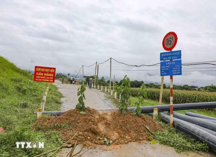 Lực lượng chức năng cắm biển cảnh báo, ngăn người và phương tiện qua cầu C9 sau khi phát hiện mố cầu bị xói lở nghiêm trọng. (Ảnh: Xuân Tư/TTXVN)