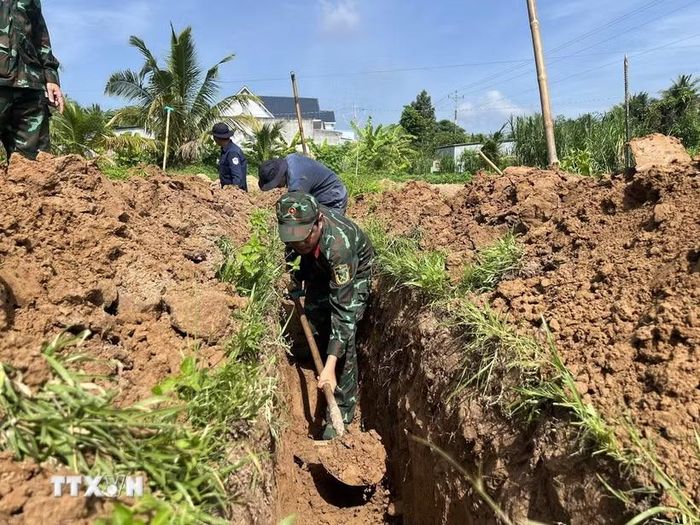 Các lực lượng khẩn trương tìm kiếm hài cốt liệt sỹ tại nghĩa trang liệt sỹ tạm ấp Tân Hòa. (Ảnh: Huỳnh Phúc Hậu/TTXVN)