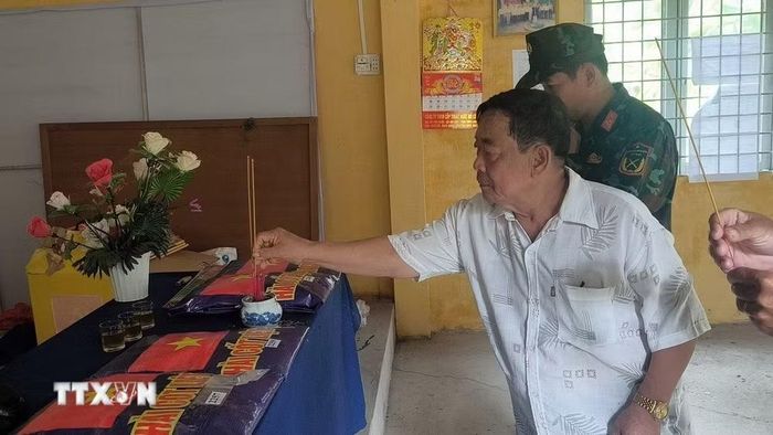 Lực lượng chức năng thắp hương viếng các liệt sỹ vừa tìm được tại Nghĩa trang liệt sỹ tạm ấp Tân Hòa. (Ảnh: Huỳnh Phúc Hậu/TTXVN)