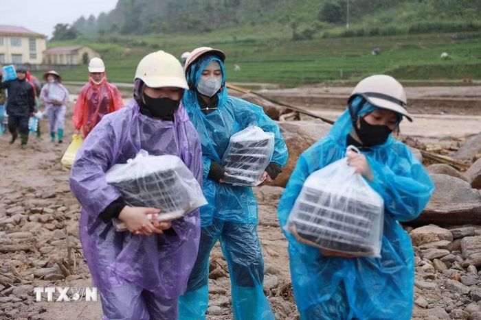 Người dân xã Than Uyên đưa những suất cơm nóng hổi ấm áp tình người cùng nhu yếu phẩm cần thiết đến với nhân dân Bản Chít và các lực lượng giúp dân khắc phục hậu quả do lũ dữ gây ra tại Mường Than. (Ảnh: Quý Trung/TTXVN)