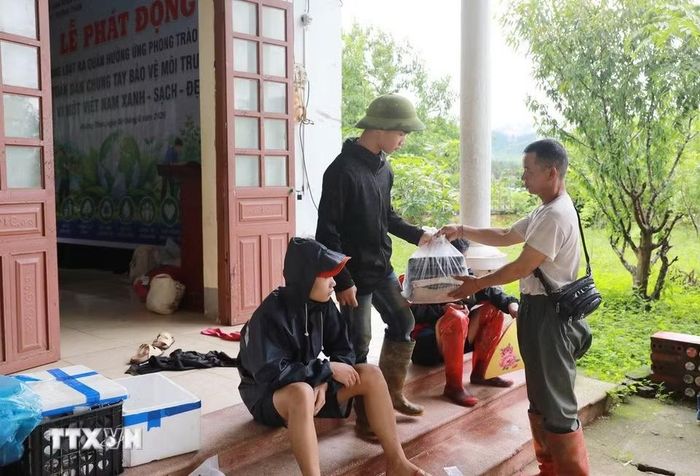 Những suất cơm ấm lòng của bà con nhân dân các xã lân cận đã đến được tay của các gia đình đang ở tạm tại Nhà văn hóa Bản Chít, đây là nơi hơn 10 hộ dân bị lũ cuốn trôi mất hết tài sản nhà cửa. (Ảnh: Quý Trung/TTXVN)