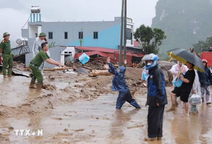 Người dân đưa nhu yếu phẩm cho các lực lượng đang hỗ trợ người dân khắc phục hậu quả của lũ dữ gây ra tại xã Mường Than. (Ảnh: Quý Trung/TTXVN)
