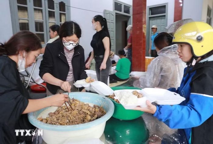 Nhân dân Bản Phúc Khoa, Không ai bảo ai, chia nhau mỗi người một việc để có những suất cơm đến sớm nhất vùng rốn lũ. (Ảnh: Quý Trung/TTXVN)