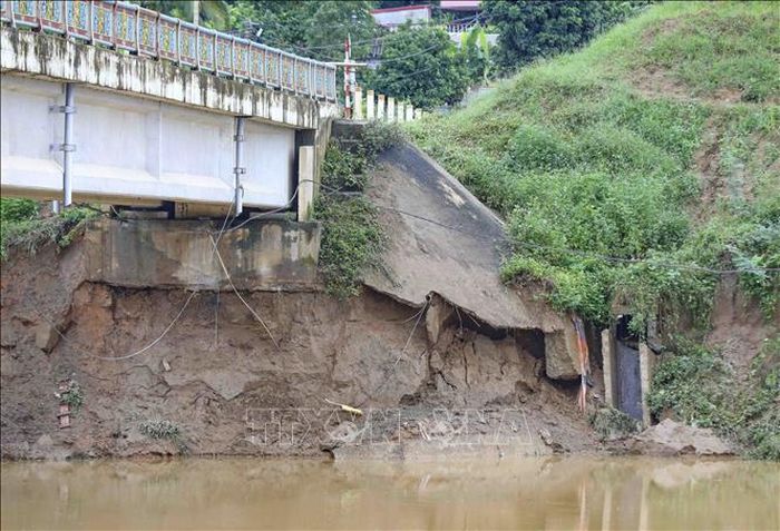 Khu vực mố cầu phía bờ sông bị sạt lở sâu, xuất hiện nhiều điểm có nguy cơ tiếp tục sụt lún. Ảnh: Xuân Tư/TTXVN.