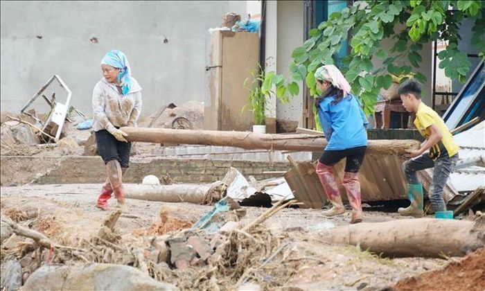 Người dân Mường Than gom củi sau khi nước lũ rút đi. Ảnh: Nguyễn Oanh/TTXVN