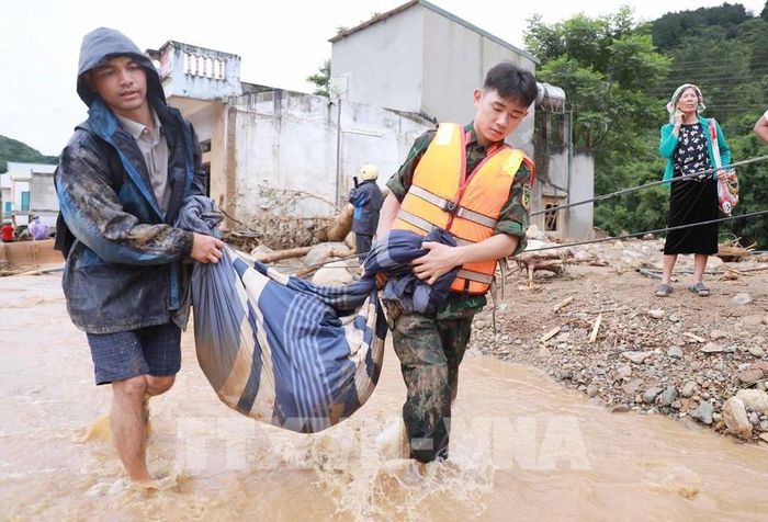 Lực lượng Công an cùng Quân đội di dời tài sản của người dân đến nơi an toàn. Ảnh: Quý Trung – TTXVN