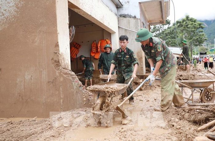 Lực lượng Quân đội giúp dân hót bùn đất, đá trôi vào nhà tại xã Mường Than. Ảnh: Quý Trung - TTXVN