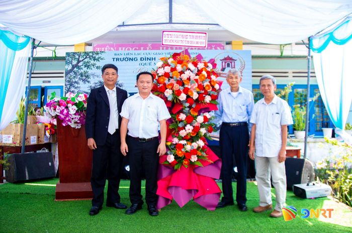 Đại diện các thế hệ cựu giáo viên, cựu học sinh Trường Đình - Phước Chỉ chụp ảnh lưu niệm bên lẵng hoa chúc mừng tại lễ kỷ niệm 45 năm ngày thành lập trường.