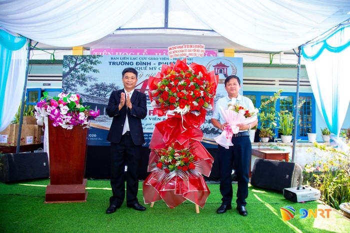 Đại diện lãnh đạo xã Quế Sơn Trung tặng hoa chúc mừng Ban Liên lạc Cựu giáo viên - học sinh Trường Đình - Phước Chỉ nhân dịp kỷ niệm 45 năm thành lập trường.