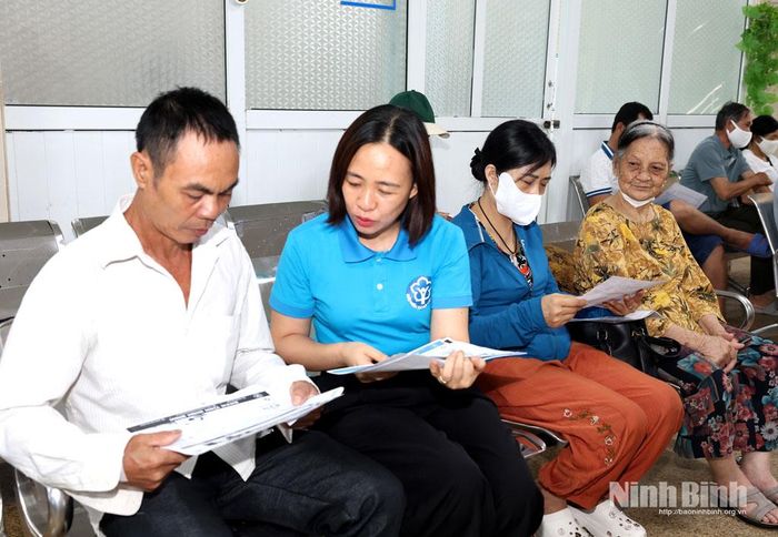 Cán bộ Bảo hiểm xã hội tỉnh phát tờ rơi tuyên truyền bảo hiểm y tế cho người dân đến khám bệnh tại Bệnh viện Đa khoa tỉnh.