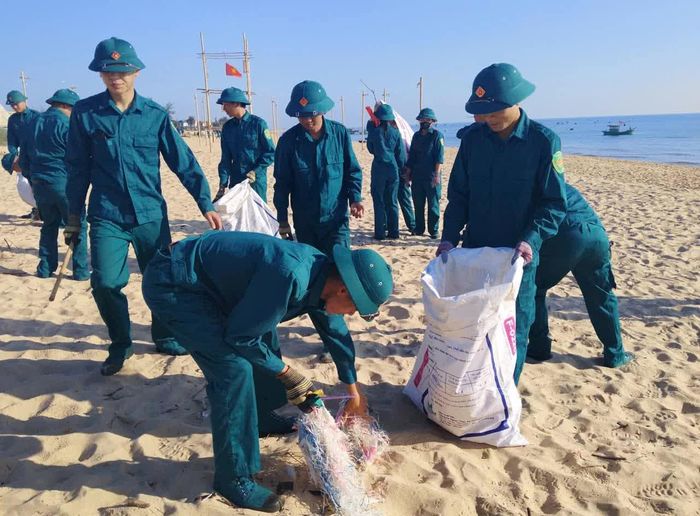 Lực lượng dân quân xã Nam Trạch tham gia làm vệ sinh bãi biển - Ảnh: P.V
