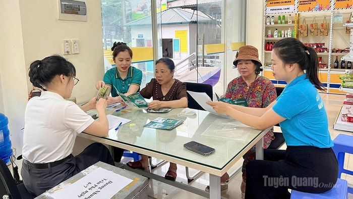 Cán bộ BHXH hỗ trợ người nhận lương hưu đăng ký nhận qua tài khoản ngân hàng.