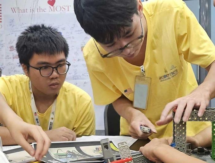 Lê Minh Quý (bên trái) hướng dẫn và hỗ trợ các em học viên cách lập trình, lắp ráp robot và khích lệ các em tự tin đặt câu hỏi, chia sẻ ý tưởng, từng bước tìm ra cách giải quyết vấn đề của chính mình. Ảnh: Hoàng Đan