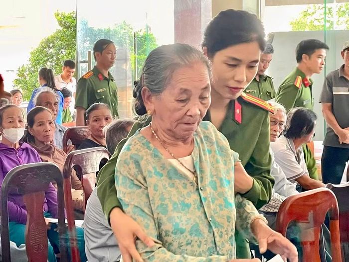 Một nữ cán bộ Công an phường Nam Đông Hà giúp đỡ một bà cụ làm thủ tục lấy mẫu ADN.