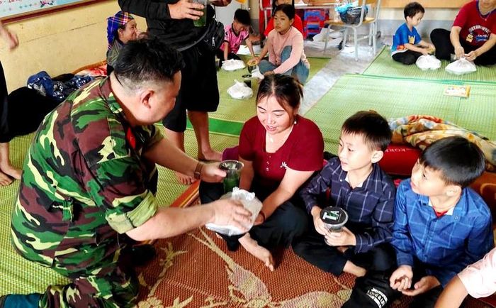 Bộ đội đưa cơm nóng đến người dân ở nơi sơ tán sau lũ quét. Ảnh: CTV