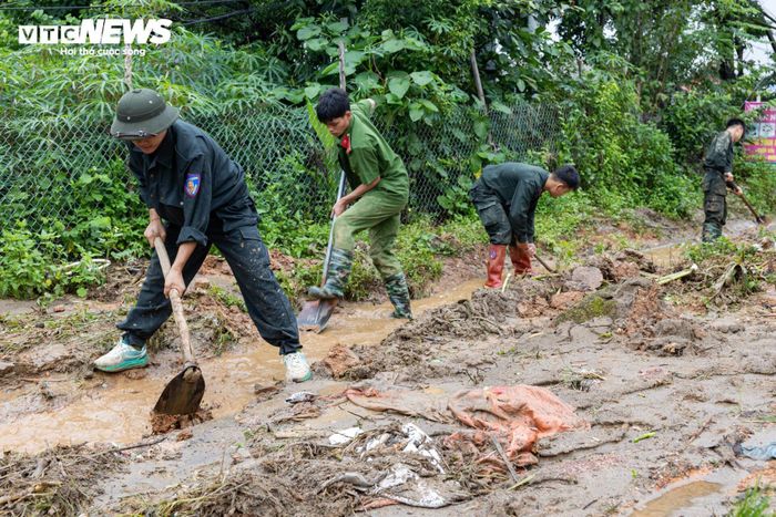 Giữa bùn đất ngổn ngang, hàng chục cán bộ, chiến sĩ công an, quân đội miệt mài giúp người dân dọn dẹp, khắc phục hậu quả lũ quét.