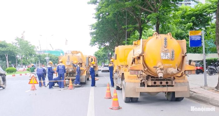 Công nhân Công ty TNHH MTV Thoát nước Hà Nội dựng rào chắn, đặt vật cảnh báo chuẩn bị làm việc. Ảnh: Lại Tấn