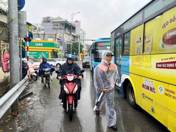 Anh Nguyễn Quốc Việt, Xí nghiệp quản lý cầu Chương Dương thực hiện nhiệm vụ trong mưa. Ảnh: Ngân Hạ