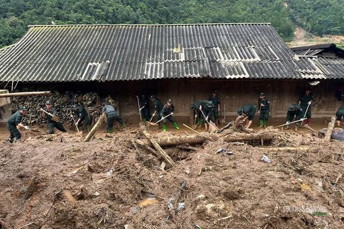 Cán bộ, chiến sĩ Cảnh sát cơ động khẩn trương thu dọn bùn đất quanh nhà dân tại xã Ngọc Chiến. Ảnh: Nguyễn Hằng