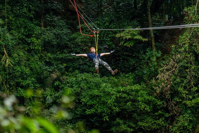 Từ đó, đơn vị phát triển hệ thống zipline (đu dây) đầu tiên tại Việt Nam băng qua hố sụt này, chính thức đưa vào vận hành từ năm 2025. Hệ thống gồm 3 dây cáp inox đạt tiêu chuẩn quốc tế, mỗi dây có tải trọng lên tới 7 tấn. Trong đó, 2 dây cáp chính kết nối với đai an toàn thông qua hệ thống ròng rọc tốc độ, còn dây thứ 3 đóng vai trò bảo hộ. Các điểm neo được bố trí độc lập và hệ thống có phanh chủ động, đảm bảo mức an toàn cao nhất cho nhà thám hiểm khi tham gia trải nghiệm.