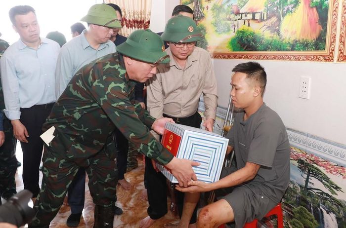 Phó Thủ tướng Chính phủ Hồ Quốc Dũng cùng các đồng chí lãnh đạo thăm hỏi, tặng quà cho anh Nguyễn Thanh Hải gia đình anh mất vợ và 2 con trong trận lũ lịch sử tại Bản Chít. Ảnh: Quý Trung – TTXVN