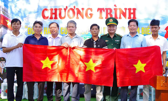Cán bộ Đồn Biên phòng Vinh Xuân trao lá cờ Tổ quốc tặng ngư dân.