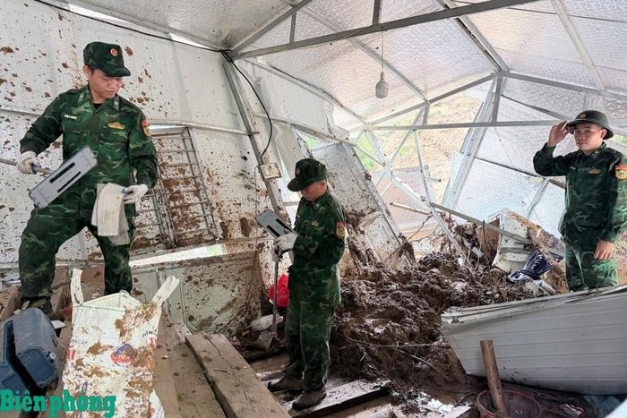 Cán bộ, chiến sĩ Bộ đội Biên phòng thu gom, di chuyển vật dụng và dọn dẹp bùn đất trong ngôi nhà bị lũ quét gây hư hỏng nặng. Ảnh: Văn Hợi