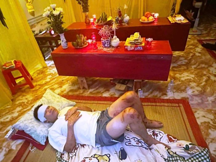 Nhói lòng hình ảnh anh Hải nằm bên linh cữu vợ và con trai. Ảnh: M.T