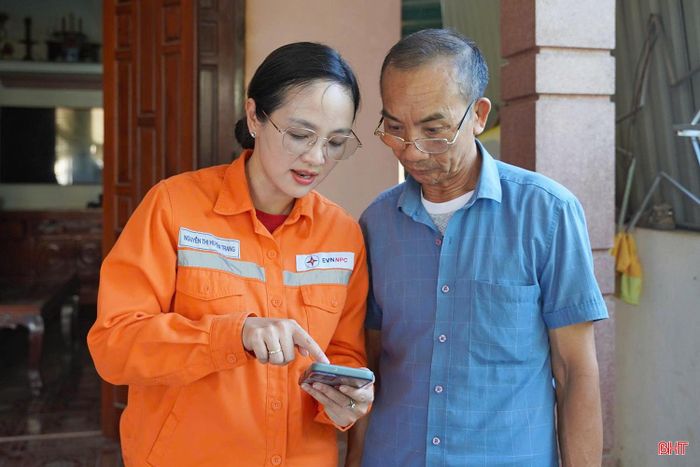 Cán bộ Điện lực Hồng Lĩnh hướng dẫn ông Dương Văn Lý (xã Trường Lưu) cài đặt và sử dụng ứng dụng EVN CSKH.