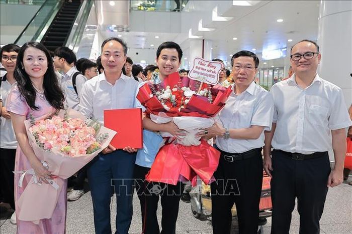 GS.TS Nguyễn Ngọc Hà, Phó Hiệu trưởng trường Đại học Sư phạm Hà Nội cùng TS. Vũ Văn Tiến, Hiệu trưởng Trường THPT Chuyên Đại học Sư phạm (Đại học Sư phạm Hà Nội) và thầy cô chúc mừng Nguyễn Lê Nhật Nam (lớp 12, THPT chuyên Đại học Sư phạm Hà Nội). Ảnh: Lê Đông/TTXVN