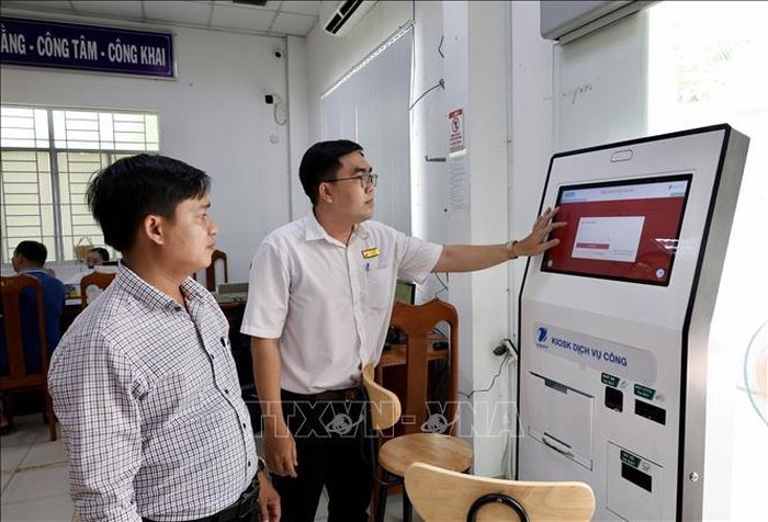 Cán bộ Trung tâm Phục vụ hành chính công phường Long Xuyên (An Giang) hướng dẫn người dân thực hiện thủ tục trực tuyến trên Cổng Dịch vụ công quốc gia. Ảnh: Thanh Sang/TTXVN