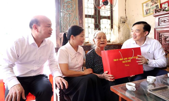 Đồng chí Nguyễn Đình Lợi, Trưởng Ban Tuyên giáo và Dân vận Tỉnh ủy trao quà cho bà Vũ Thị Năm.