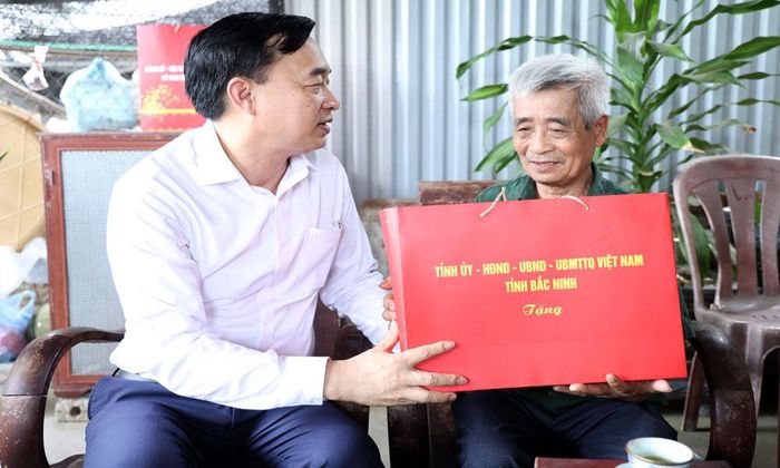 Đồng chí Nguyễn Đình Lợi, Trưởng Ban Tuyên giáo và Dân vận Tỉnh ủy trao quà cho ông Trần Thế Dục.