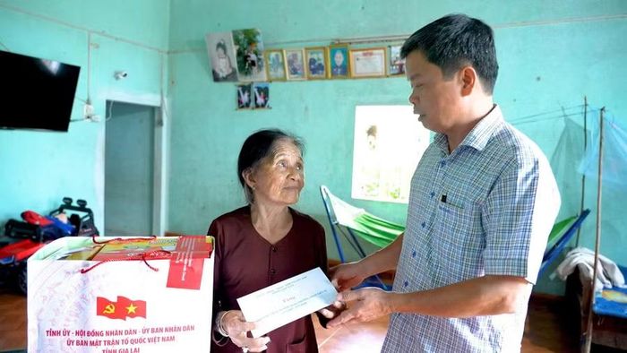 Phó Chủ tịch UBND tỉnh Nguyễn Hữu Quế tặng quà cho bà Võ Thị Dây (thân nhân liệt sĩ, ở thôn Tân Quang, xã Canh Vinh). Ảnh: Dũng Nhân