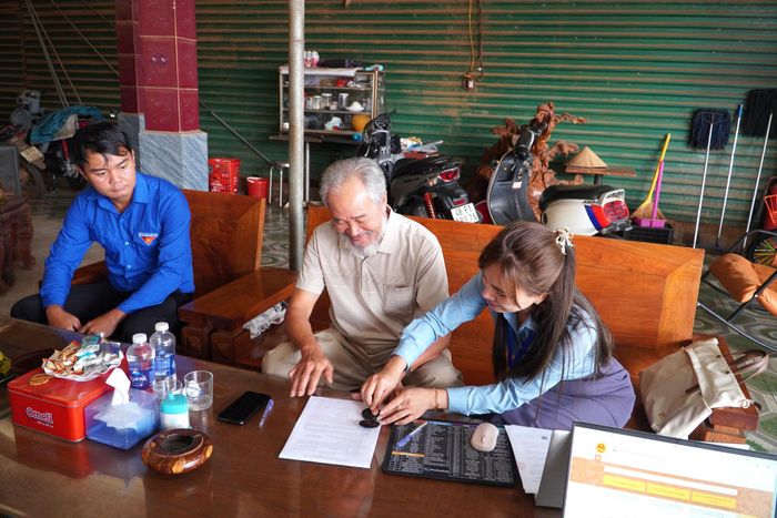 Ông Trần Văn Phối (ngồi giữa) phấn khởi khi được các thành viên Đội ứng cứu giải quyết TTHC xã hướng dẫn làm một số thủ tục hành chính tại nhà