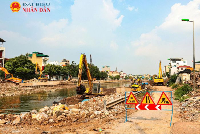 Các công nhân cùng máy móc thiết bị được huy động thi công đồng loạt các hạng mục kè bê tông, nạo vét lòng sông gần trạm bơm Yên Sở