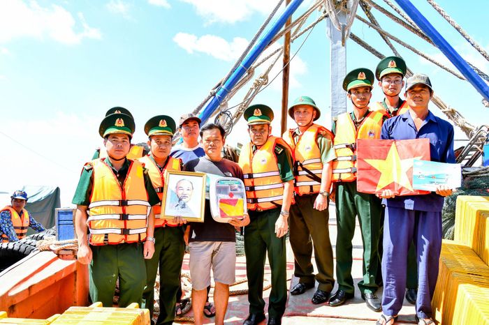 Lãnh đạo BĐBP và các đơn vị tham gia ra quân tuần tra, kiểm tra, kiểm soát trao tặng cờ Tổ quốc, ảnh Bác Hồ và tủ thuốc Biên phòng cho các chủ phương tiện khai thác đánh bắt thủy hải sản trên biển. Ảnh: Văn Long