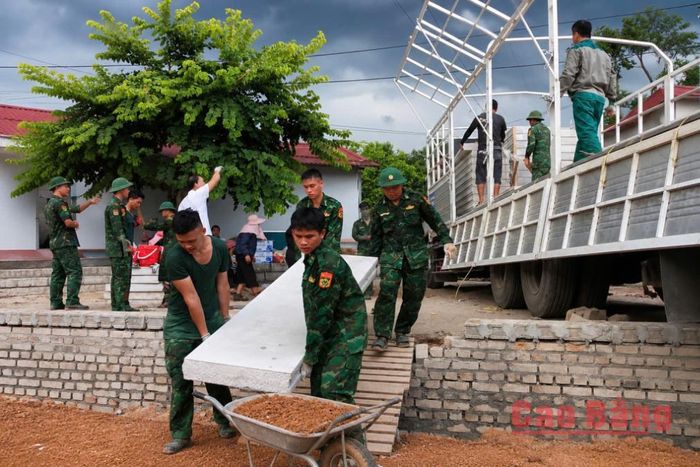 Cán bộ, chiến sĩ biên phòng và người dân phối hợp vận chuyển vật liệu.