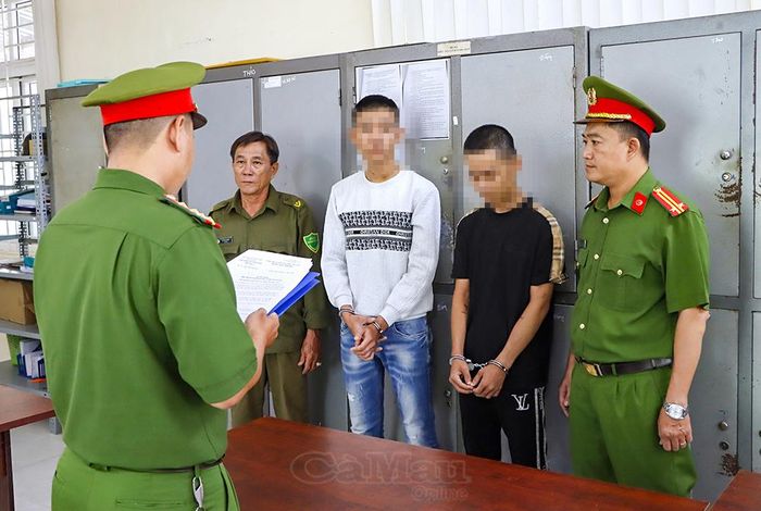 Cơ quan Cảnh sát điều tra Công an tỉnh Cà Mau tống đạt quyết định khởi tố bị can và lệnh bắt tạm giam đối với Lê Trường Vửng (áo đen) và Nguyễn Chí Hùng (áo trắng) để điều tra về hành vi "Gây rối trật tự công cộng".
