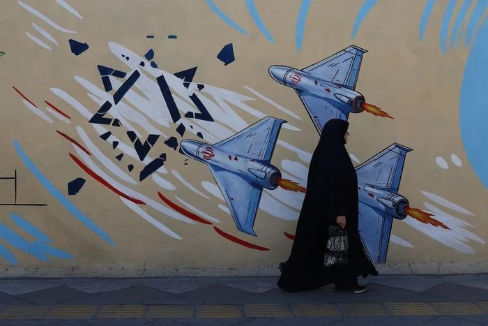  Một người phụ nữ Iran đi ngang qua bức tường sơn hình tên lửa ở Tehran. Ảnh: Reuters. 