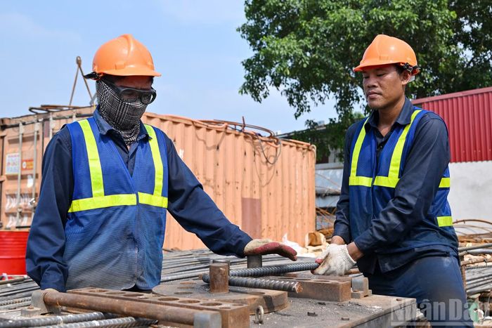 Trên công trường, các công nhân làm việc 3 ca, cả ngày lẫn đêm, nhiều máy móc, xà lan hoạt động liên tục hai bên bờ và giữa sông Hồng.