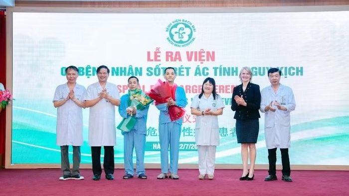 Hai bệnh nhân nhận hoa chúc mừng của thầy thuốc trước khi ra viện.