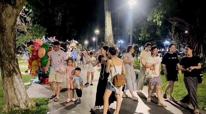 Người dân và khách du lịch dạo bộ, tận hưởng không khí mát mẻ trên tuyến đường ven sông Hương vào buổi tối.