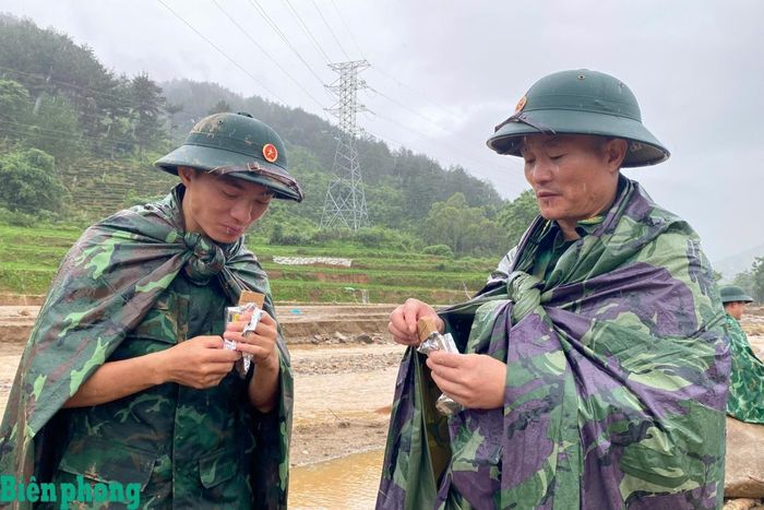 Giữa cơn mưa nặng hạt, cán bộ, chiến sĩ tranh thủ ăn lương khô ngay tại hiện trường trước khi tiếp tục nhiệm vụ tìm kiếm người mất tích. Ảnh: Văn Hợi
