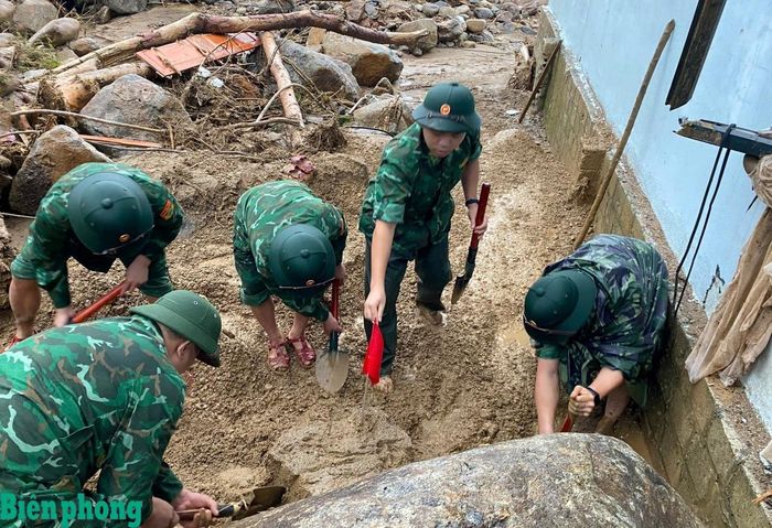 Cán bộ, chiến sĩ cắm cờ đánh dấu, tập trung đào lớp bùn đất dày và những khối đá lớn tại vị trí nghi có nạn nhân bị vùi lấp. Ảnh: Văn Hợi