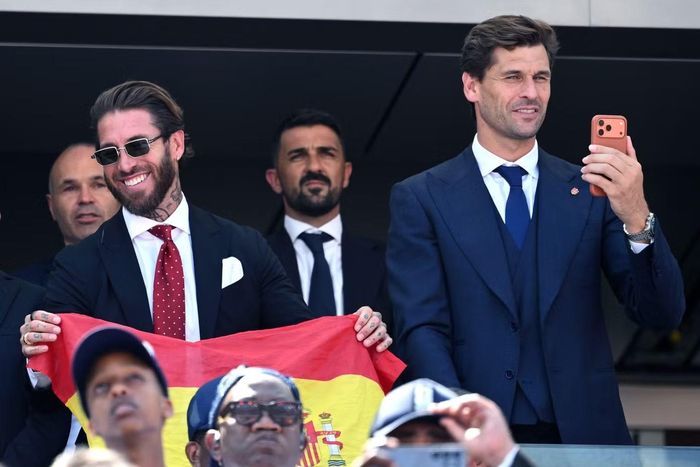 Sergio Ramos rạng rỡ giương quốc kỳ Tây Ban Nha bên cạnh cựu tiền đạo Fernando Llorente. Ở tuổi 40, Ramos vẫn thu hút ống kính nhờ vóc dáng săn chắc, mái tóc chải ngược, bộ râu được chăm chút kỹ cùng cách phối suit lịch lãm.