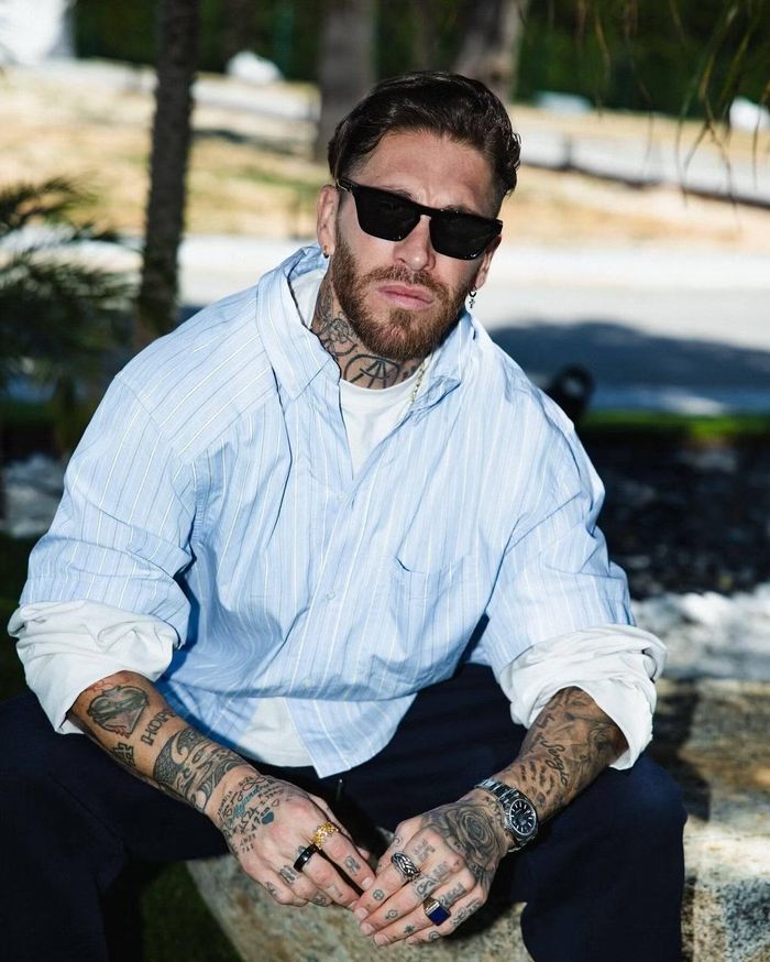 Ngoài đời thường, Sergio Ramos theo đuổi phong cách phóng khoáng nhưng vẫn giữ vẻ nam tính. Sơ mi kẻ sáng màu, kính đen, đồng hồ kim loại và nhiều nhẫn được kết hợp có chủ ý, vừa làm nổi bật hình xăm đặc trưng, vừa tạo diện mạo trẻ trung cho cựu thủ quân Tây Ban Nha ở tuổi 40.