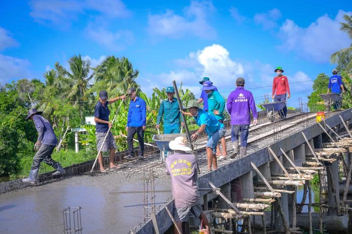 Từ sáng sớm, công trường đã nhộn nhịp. Những chuyến xe rùa chở cát, đá liên tục nối đuôi nhau, từng bao xi măng được chuyền tay, những thanh sắt được buộc chắc chắn trước khi đổ bê tông xuống mặt cầu. Dưới cái nắng oi ả, mồ hôi thấm đẫm trên gương mặt mỗi người nhưng không ai ngơi tay.